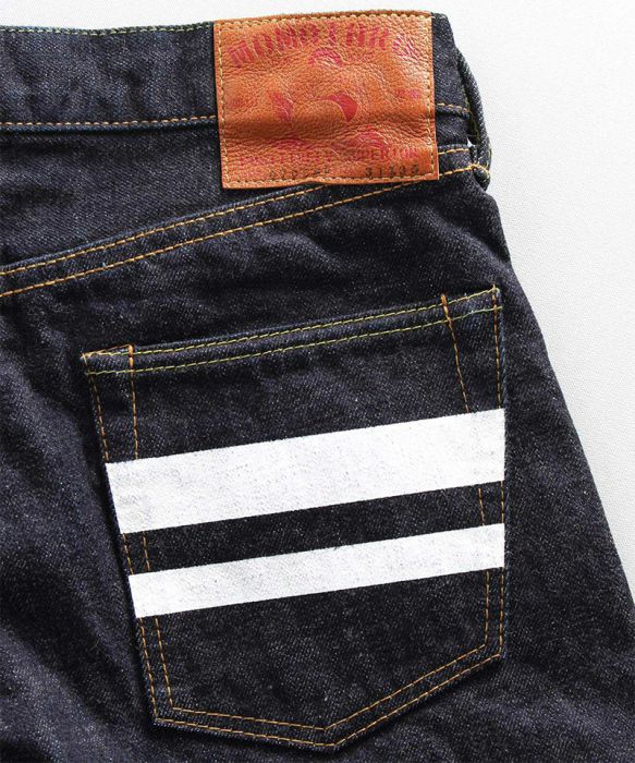 Black denim jeans back pocket with two white horizontal stripes and a brown leather label