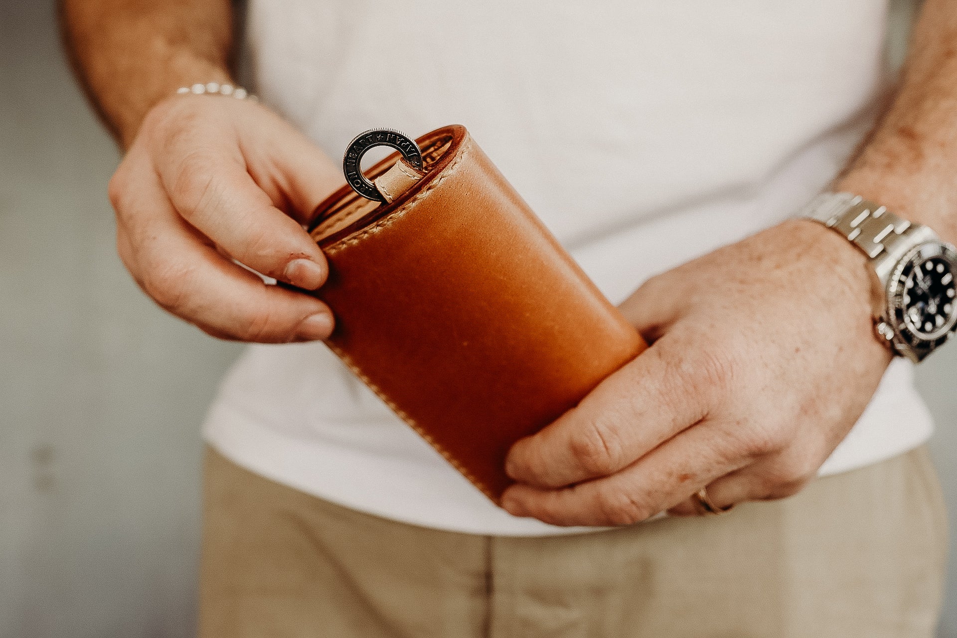 Man holding tan Iron Shop Provisions shell cordovan leather wallet with metal pull tab
