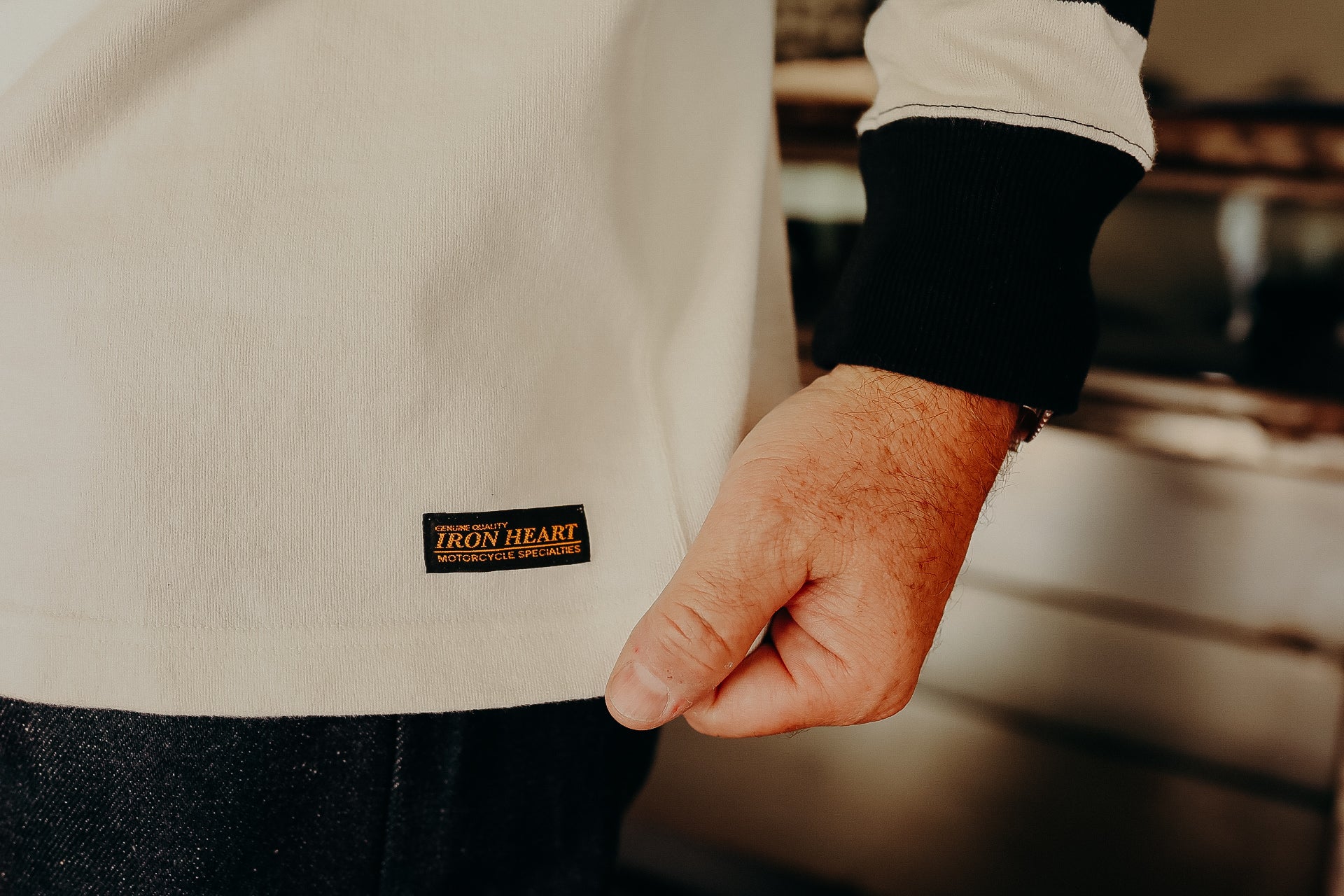 Close-up of a beige Iron Heart branded shirt cuff with black sleeve detail worn by a person