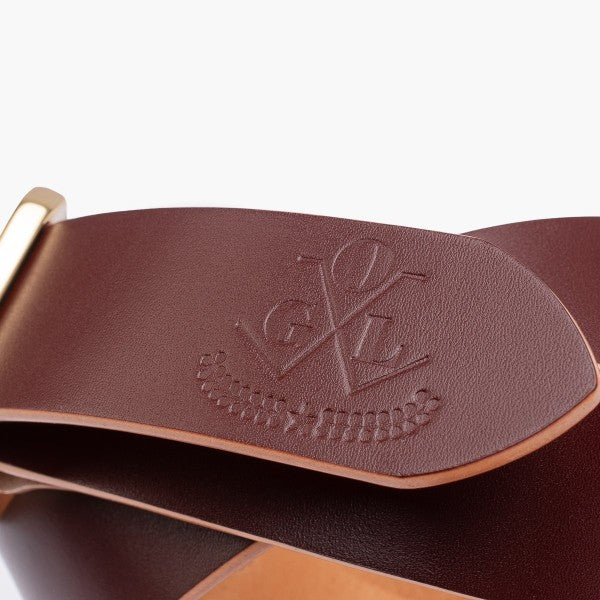 Close-up of brown leather belt with embossed GVL logo and brass buckle from Iron Shop Provisions