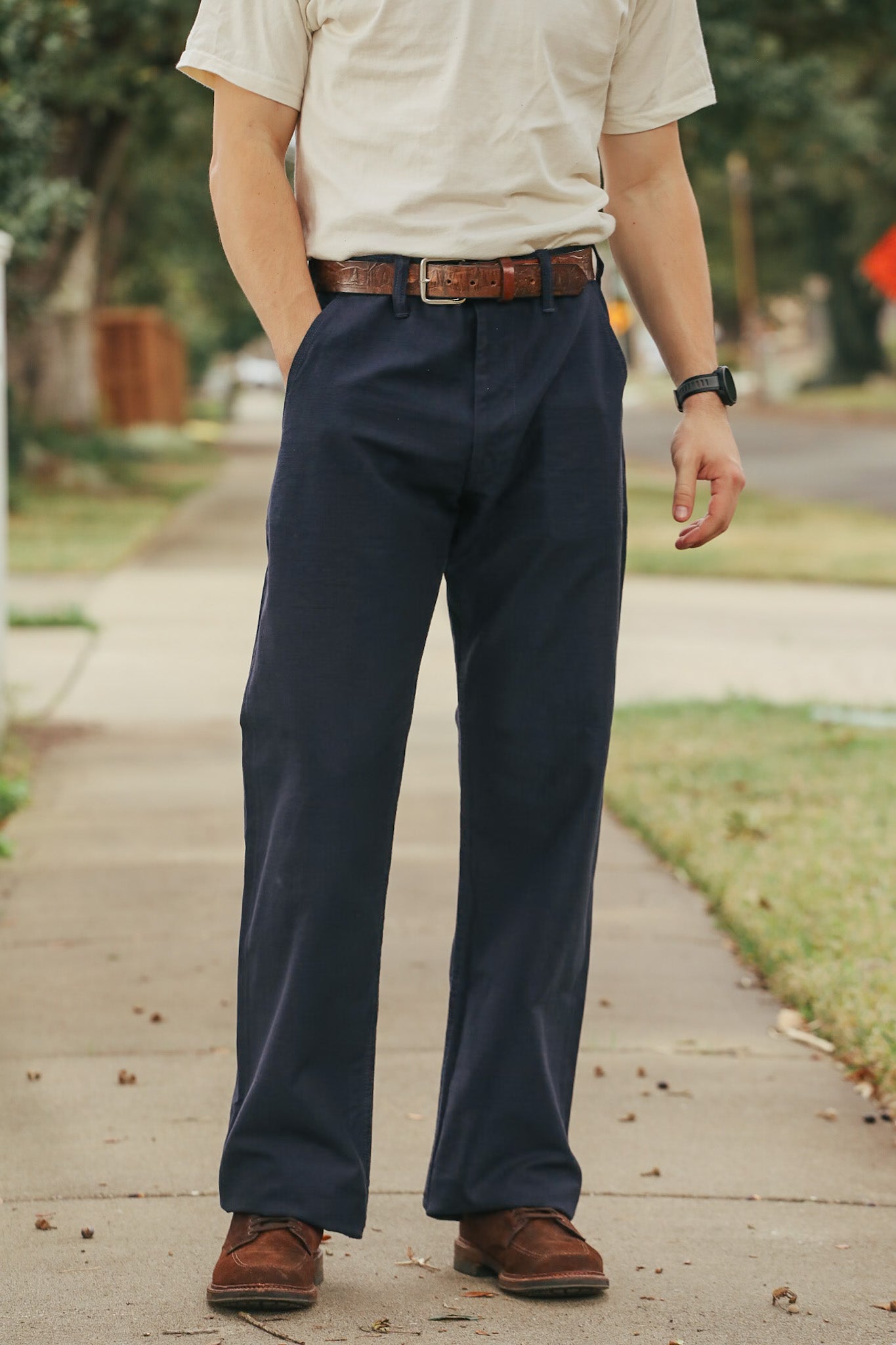Person wearing navy pants and a beige shirt on a sidewalk.