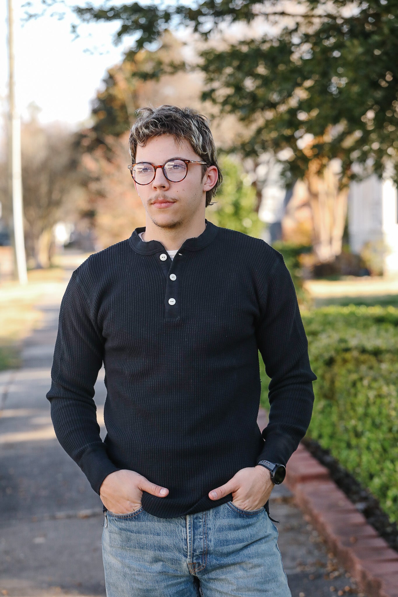 Person wearing a black long-sleeve shirt and glasses outdoors.