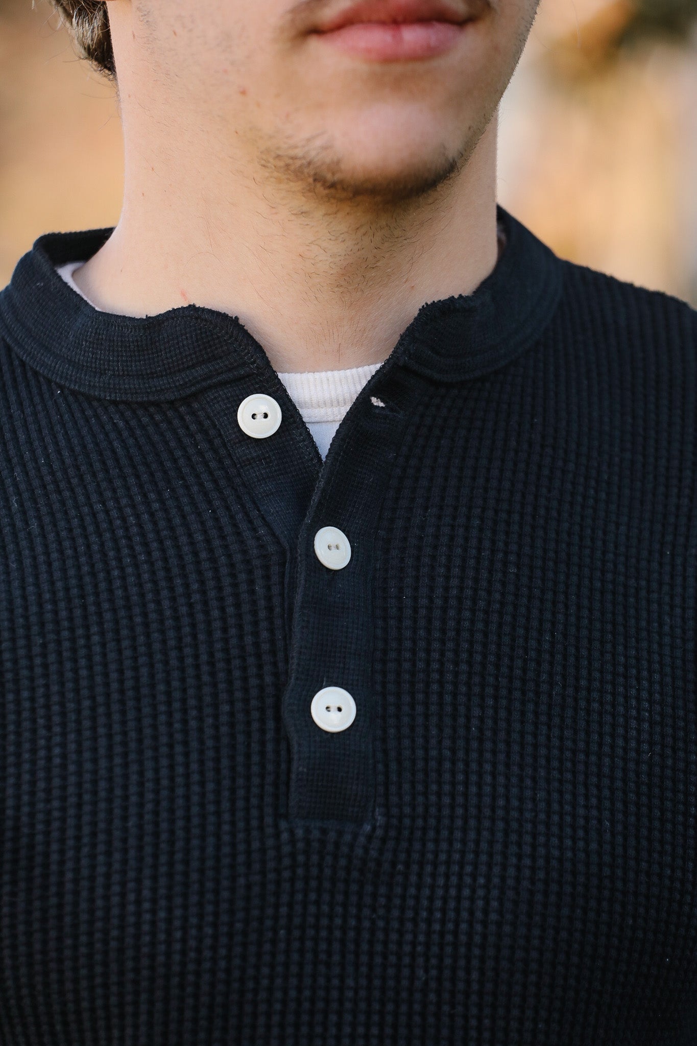 Close-up of a person wearing a dark blue button-up shirt with a blurred background