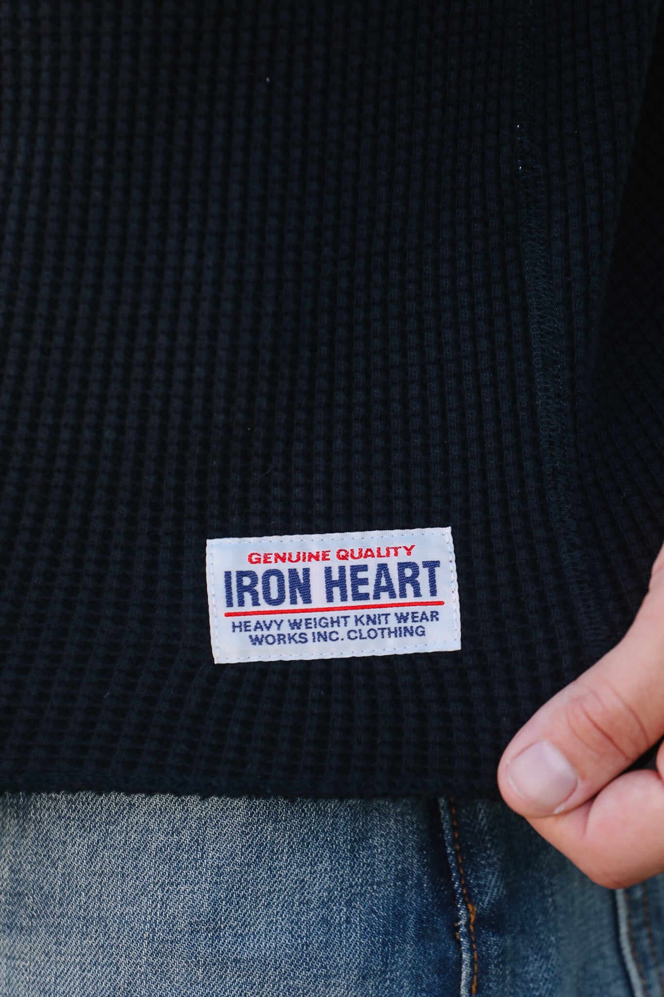 Close-up of a black garment with an Iron Heart label on a plain background