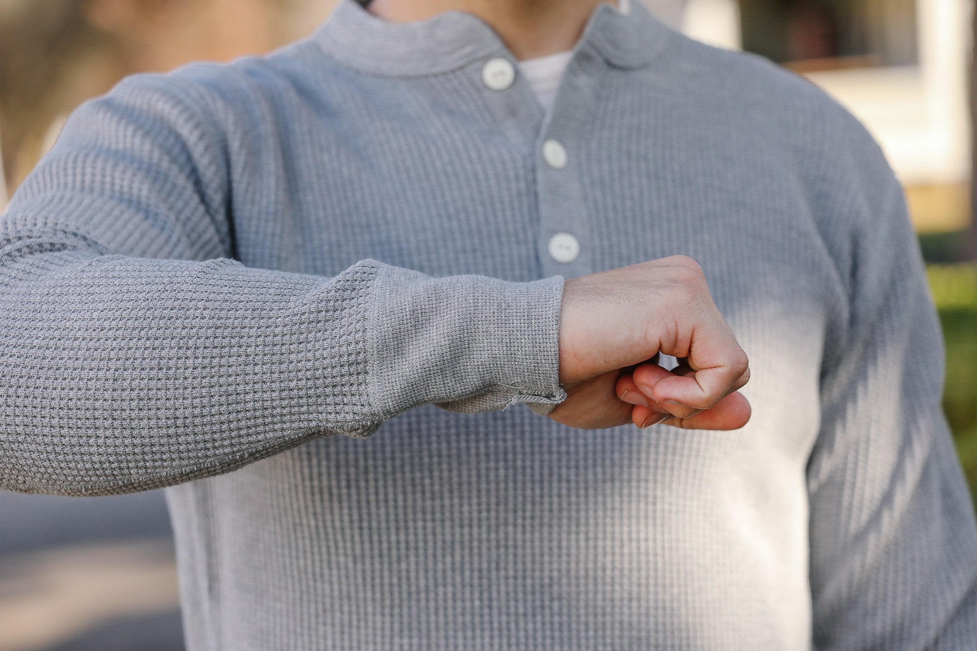 Person wearing a gray textured shirt with a blurred background