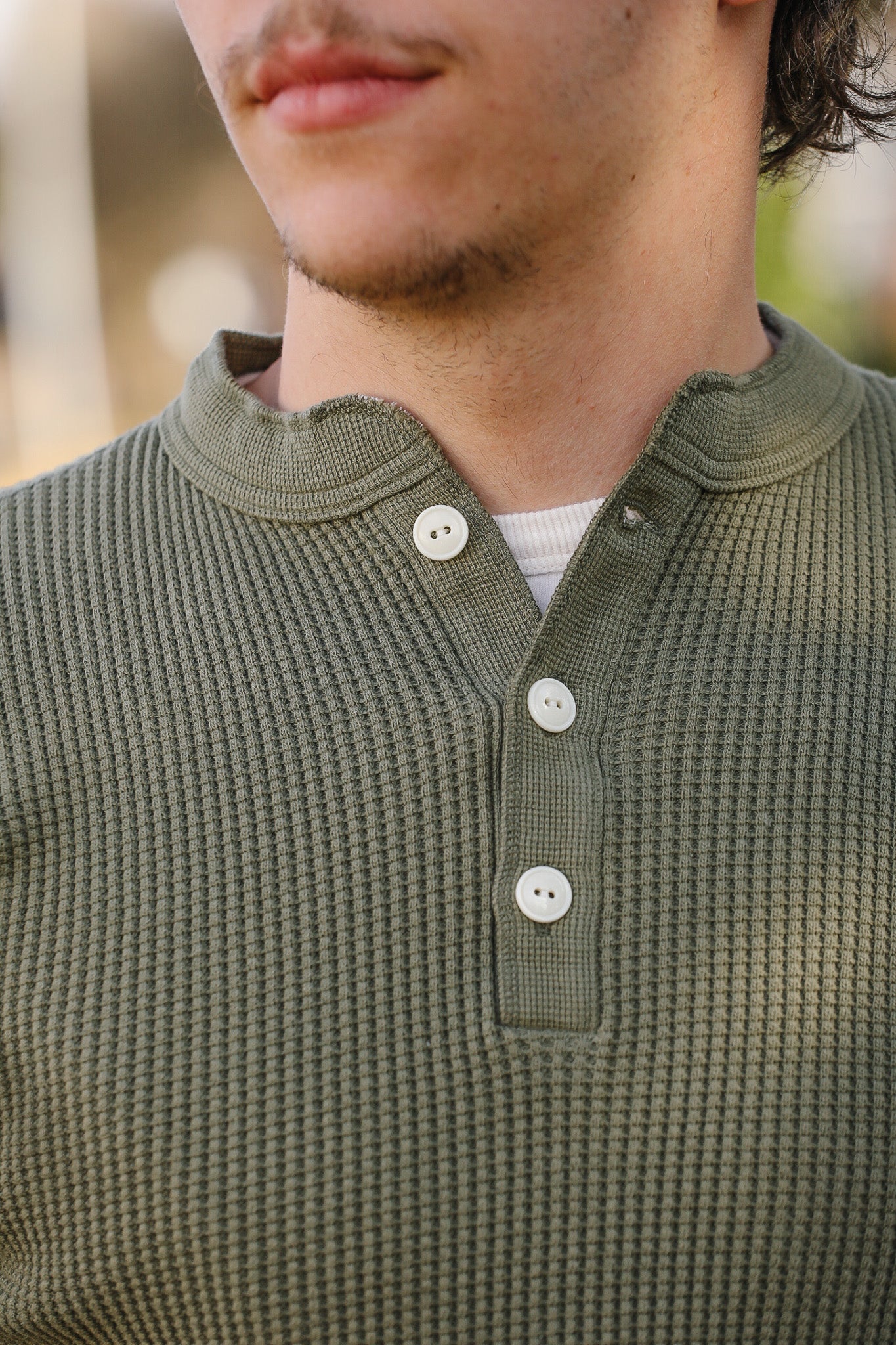 Close-up of a person wearing a green textured shirt with buttons.