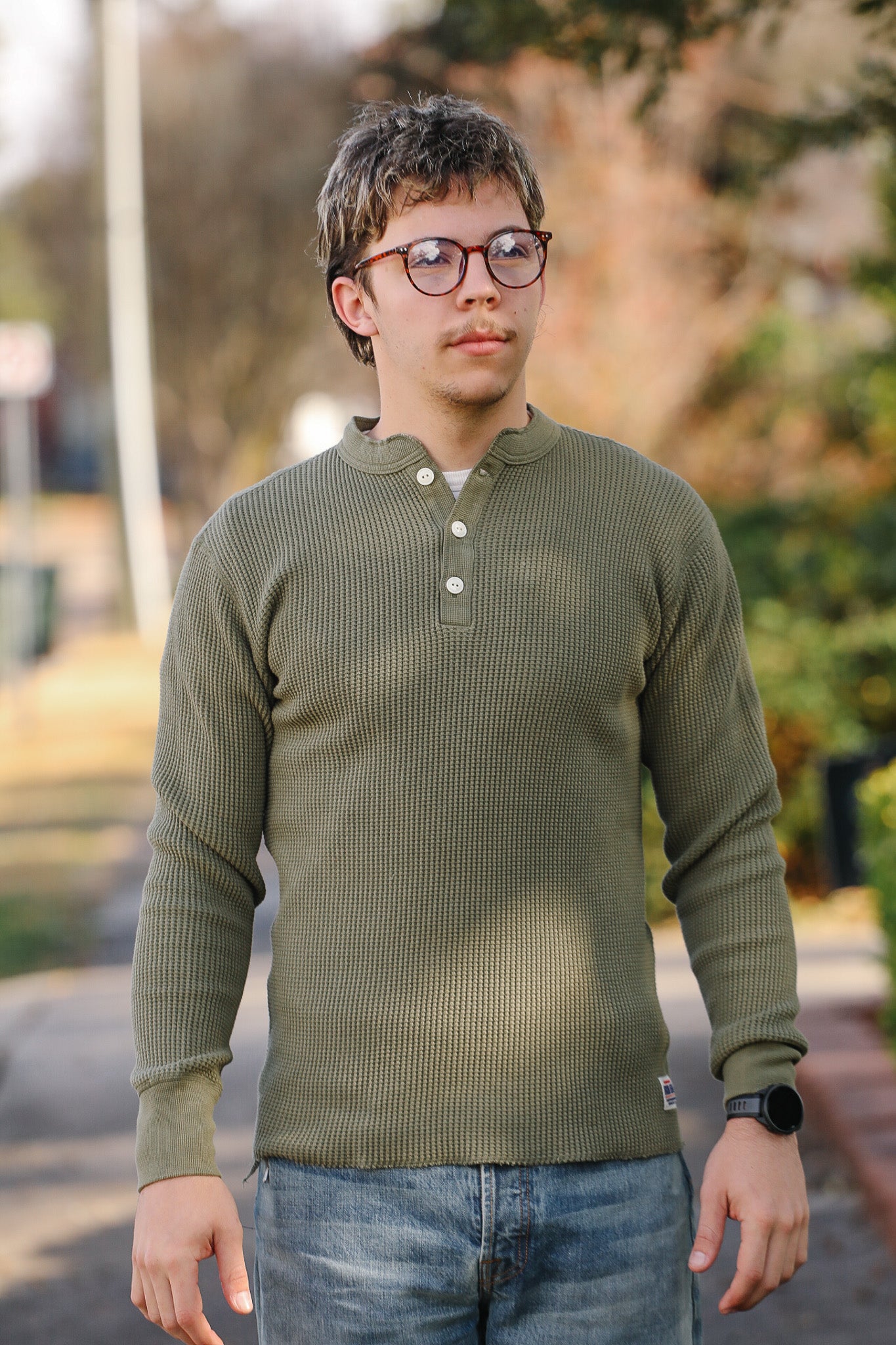 Man wearing a green long-sleeve shirt and glasses outdoors