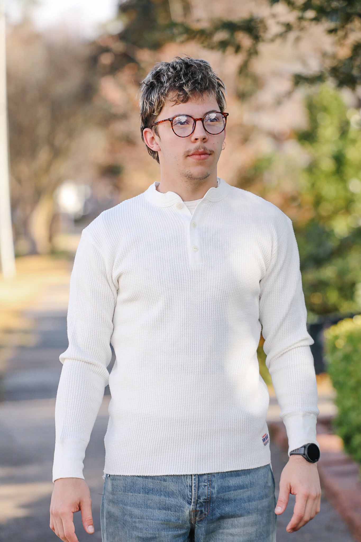 Person wearing a white sweater and glasses outdoors