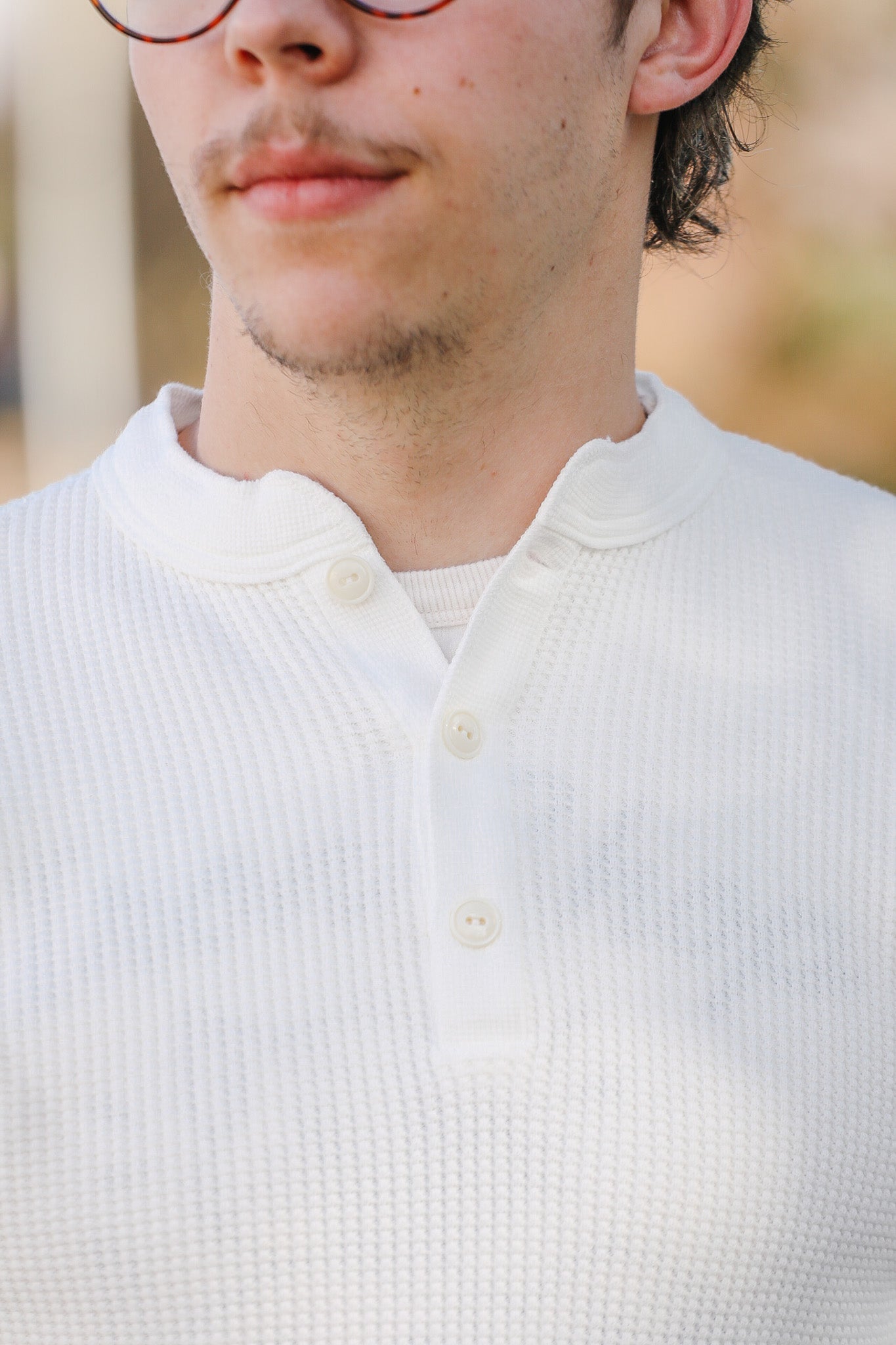 Close-up of a person wearing a white button-up shirt with a blurred background
