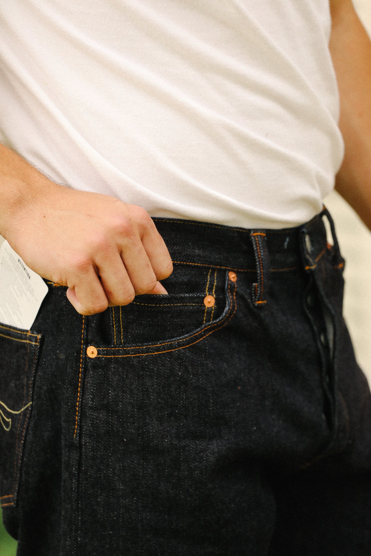 Close-up of person wearing 18oz indigo wide taper jeans from Iron Shop Provisions with hand in pocket and white shirt