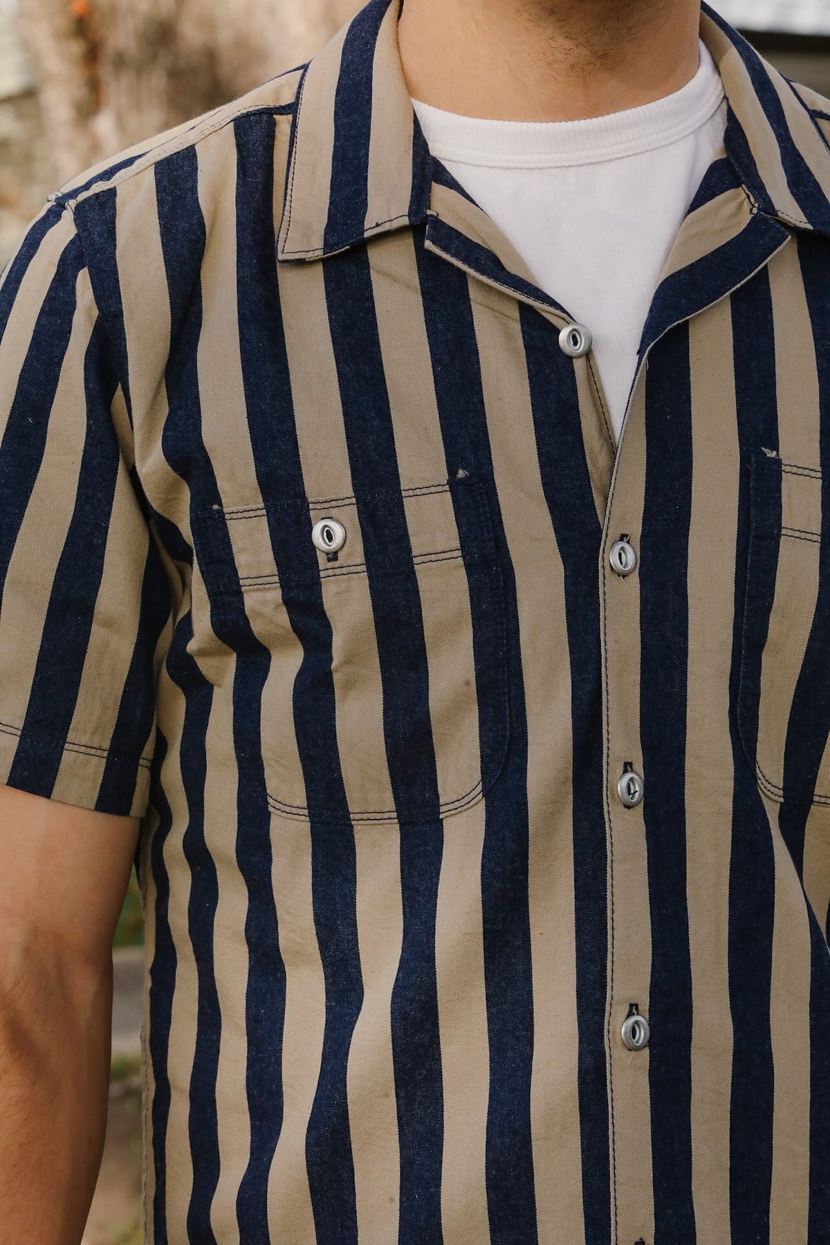 Person wearing a striped shirt with navy and beige vertical stripes.