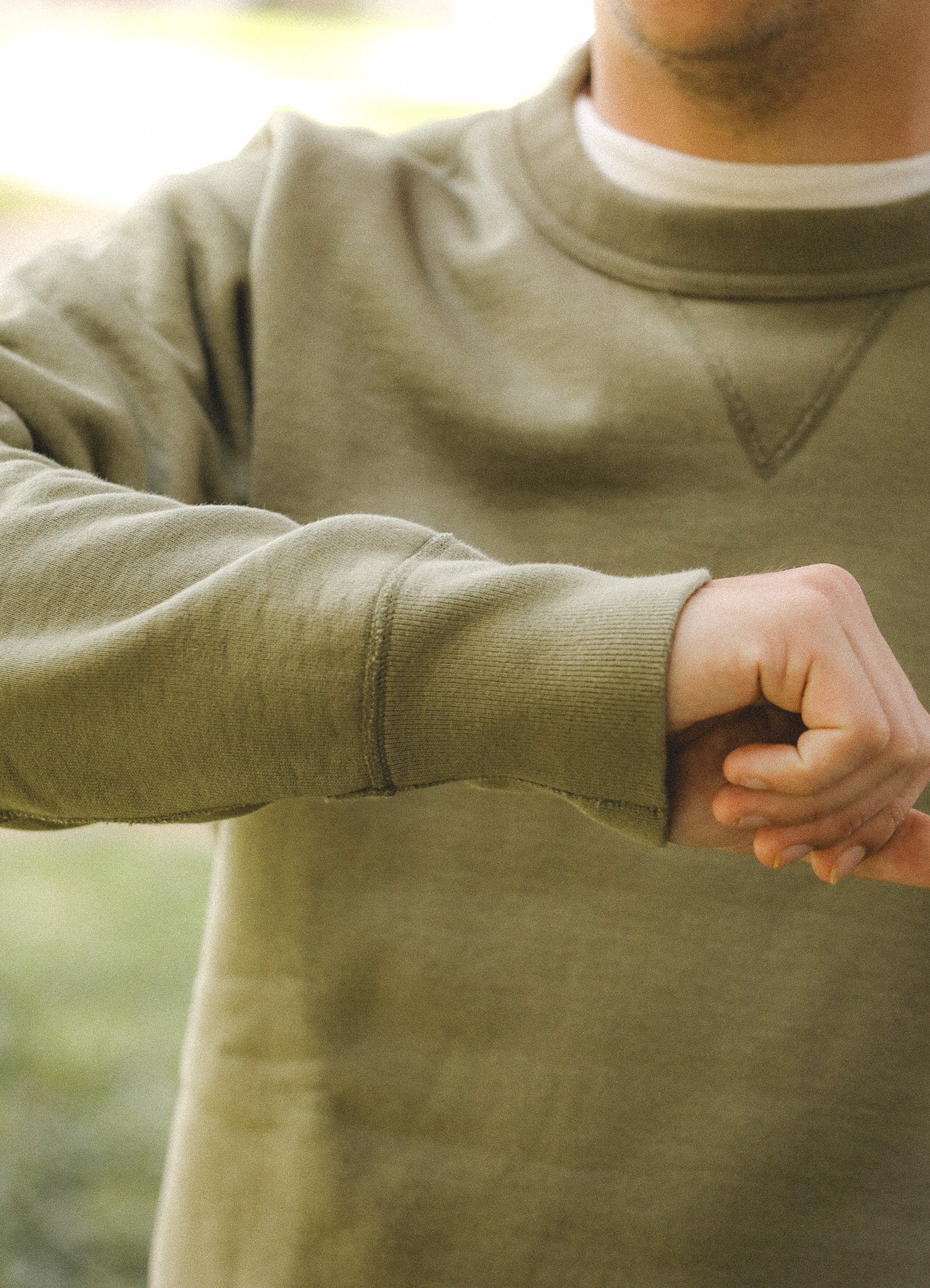 Person wearing a green sweatshirt with a blurred natural background
