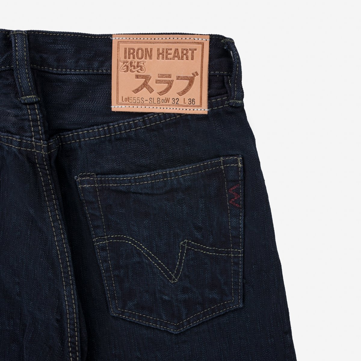 Dark blue Iron Heart denim jeans close-up showing back pocket and leather brand patch with Japanese text