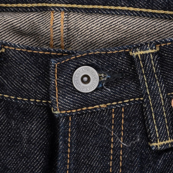 Close-up of dark denim jeans waistband with visible button and yellow stitching detail