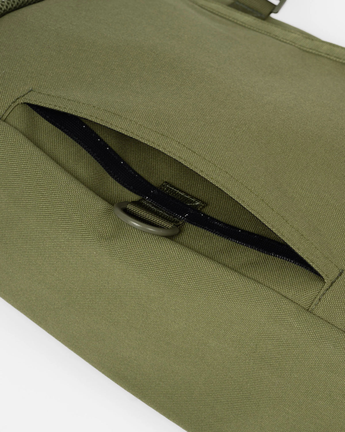 Close-up of an olive green canvas bag with a zippered pocket and a dark metal D-ring closure.