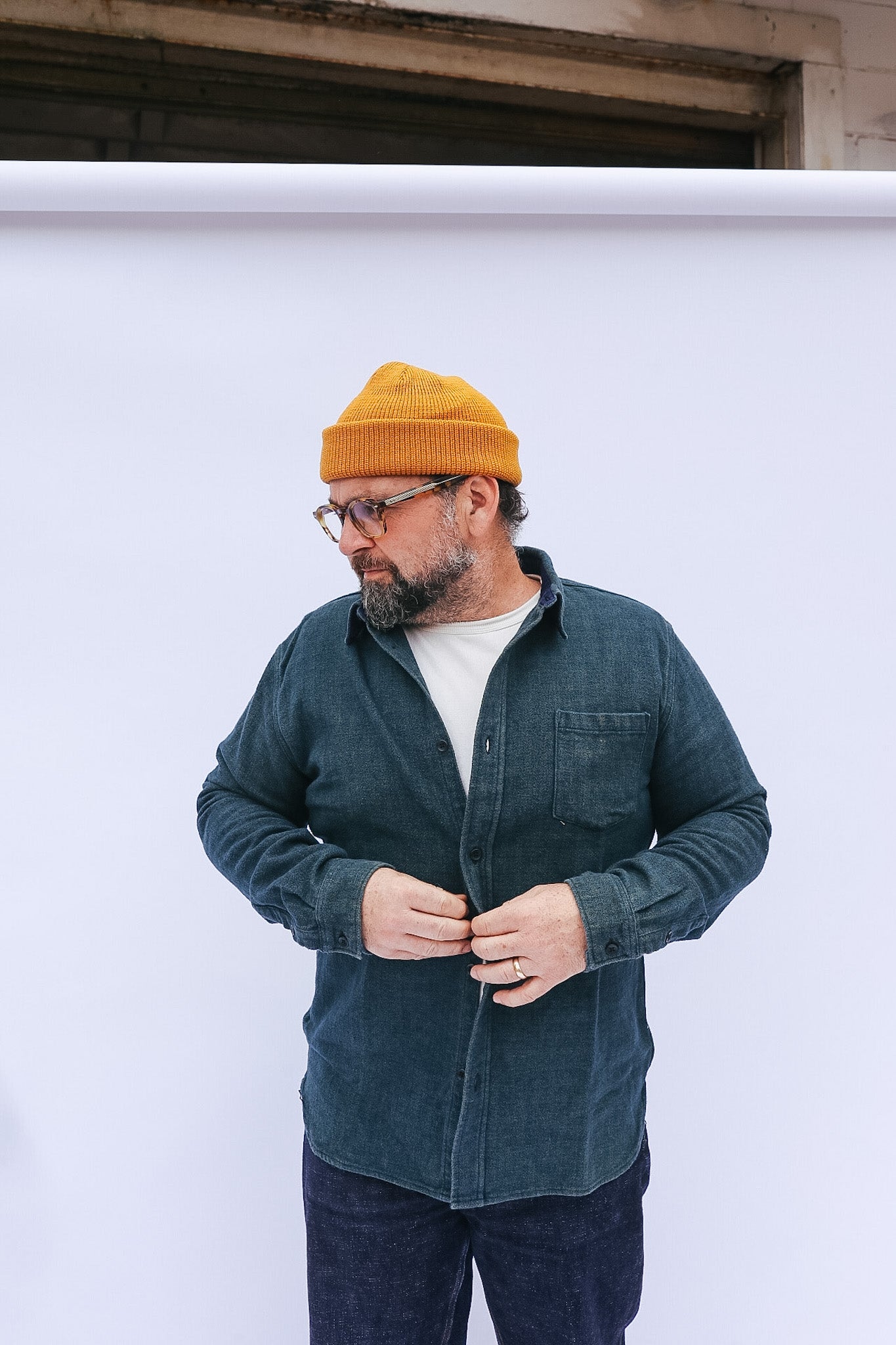 Man wearing a yellow beanie and dark jacket against a white background
