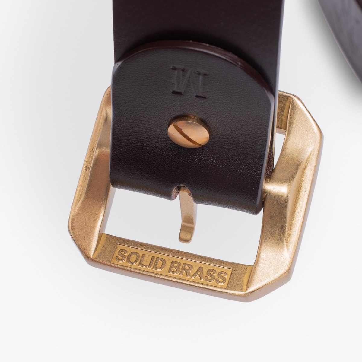 Close-up of black leather belt with solid brass buckle and engraved text on buckle