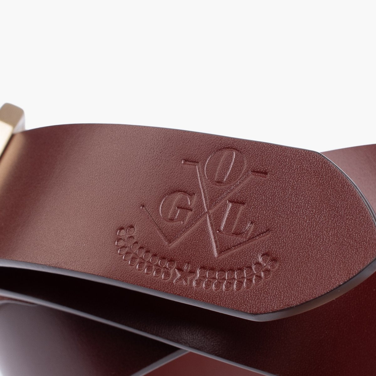 Close-up of brown leather belt with embossed logo and brass buckle detail