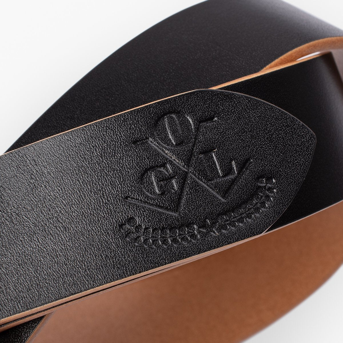 Black leather belt with embossed logo and smooth tan interior, crafted by Iron Shop Provisions