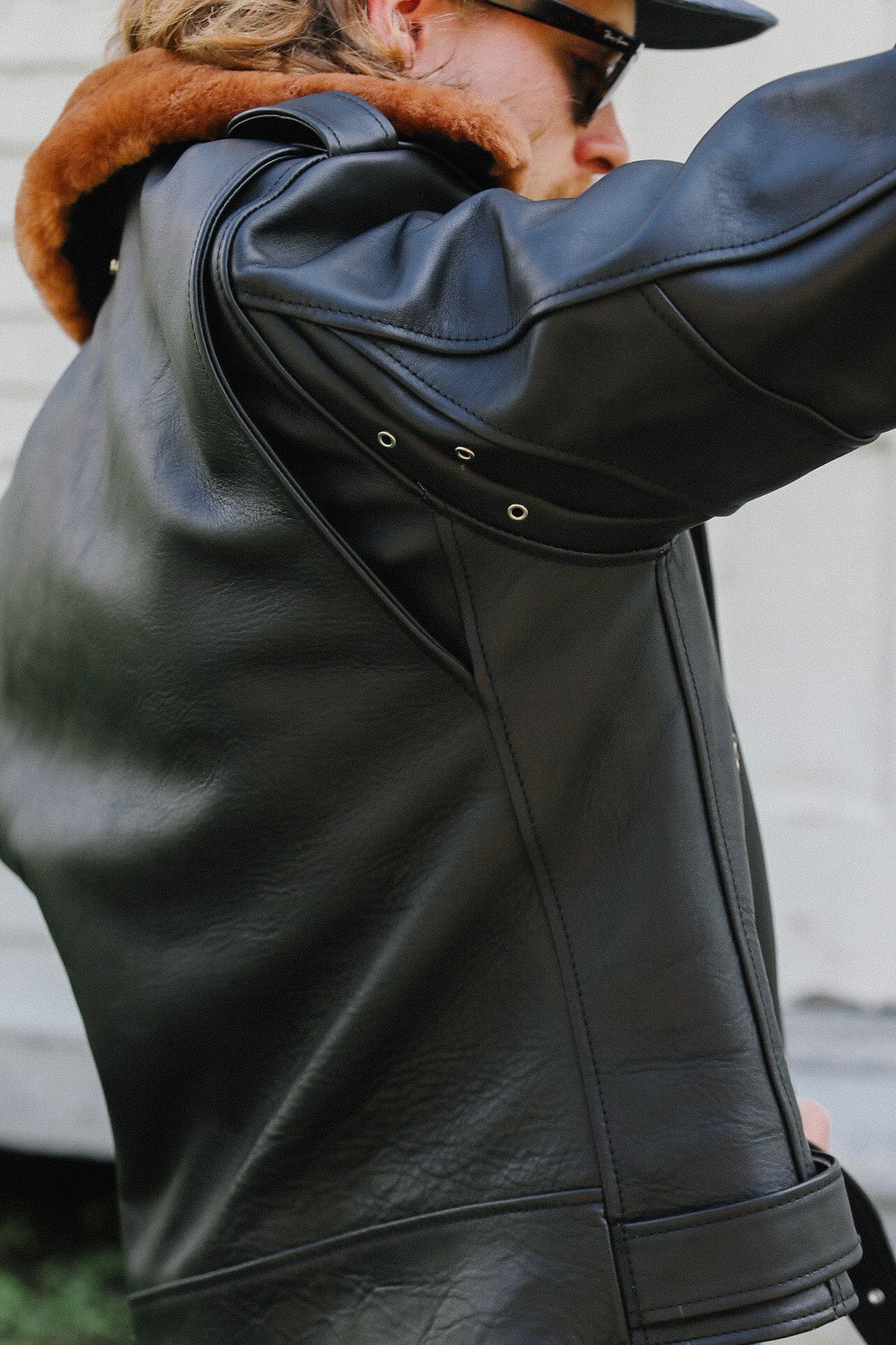 Close-up of man wearing black saddle-dyed horsehide leather jacket with shearling collar and eyelets
