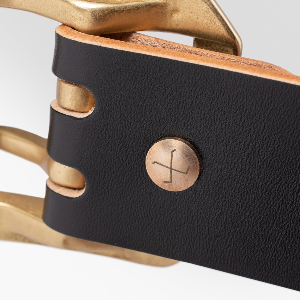 Close-up of black leather belt with brass buckle and engraved rivet from Iron Shop Provisions