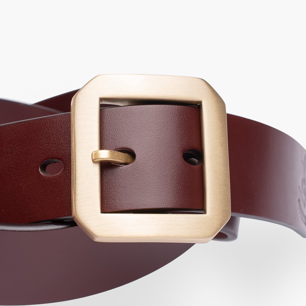 Close-up of a brown leather belt with a square brass buckle from Iron Shop Provisions