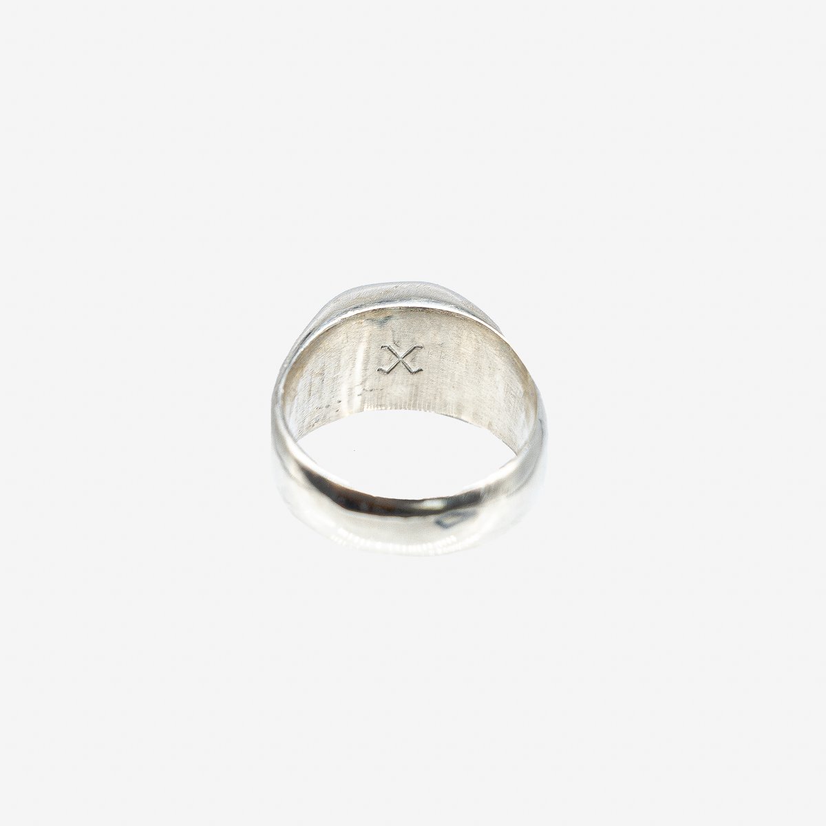 Silver ring with a minimalist crossed design engraved inside, photographed on white background