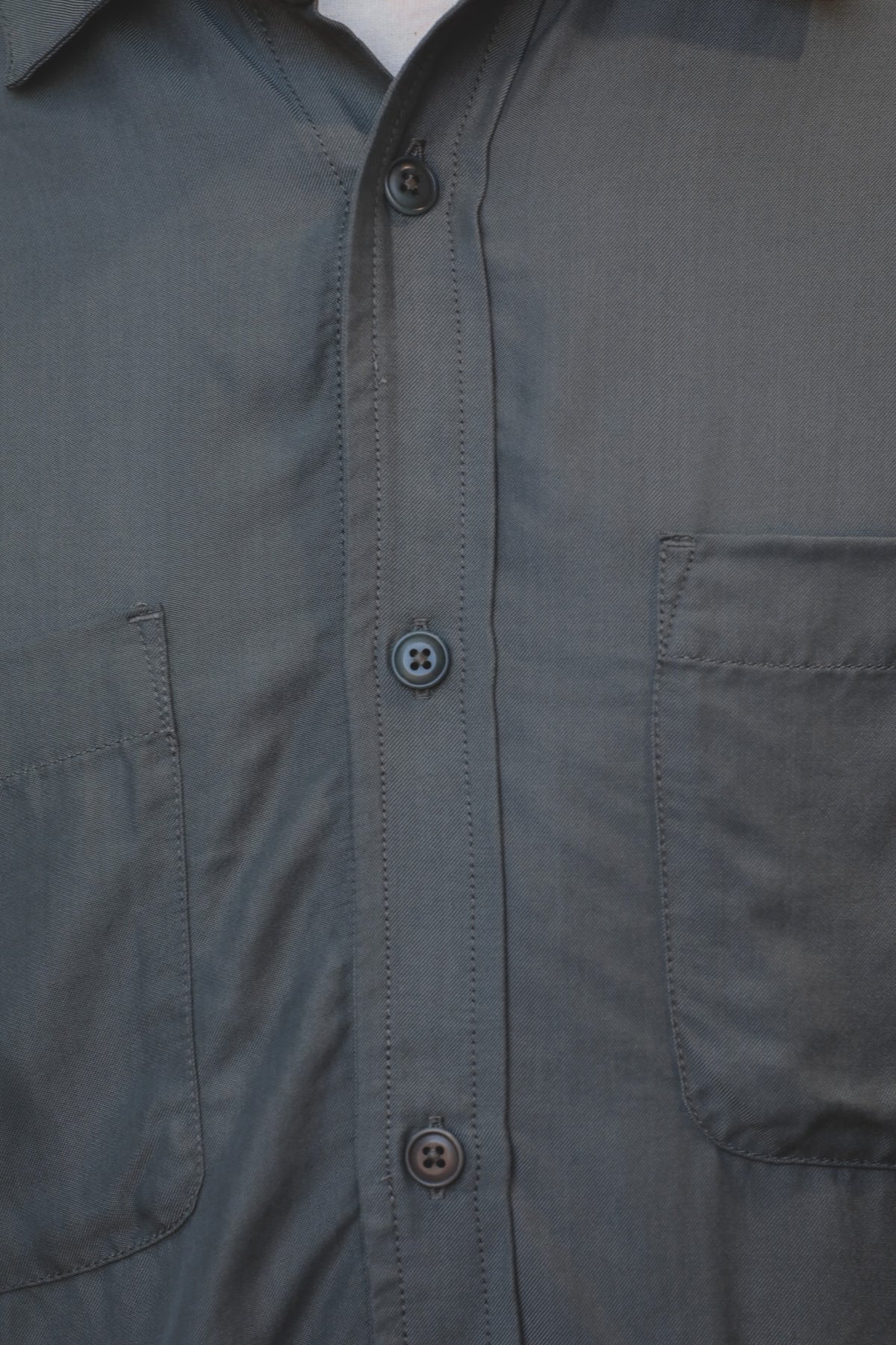 Close-up of a dark gray button-down shirt with a chest pocket and button closure.