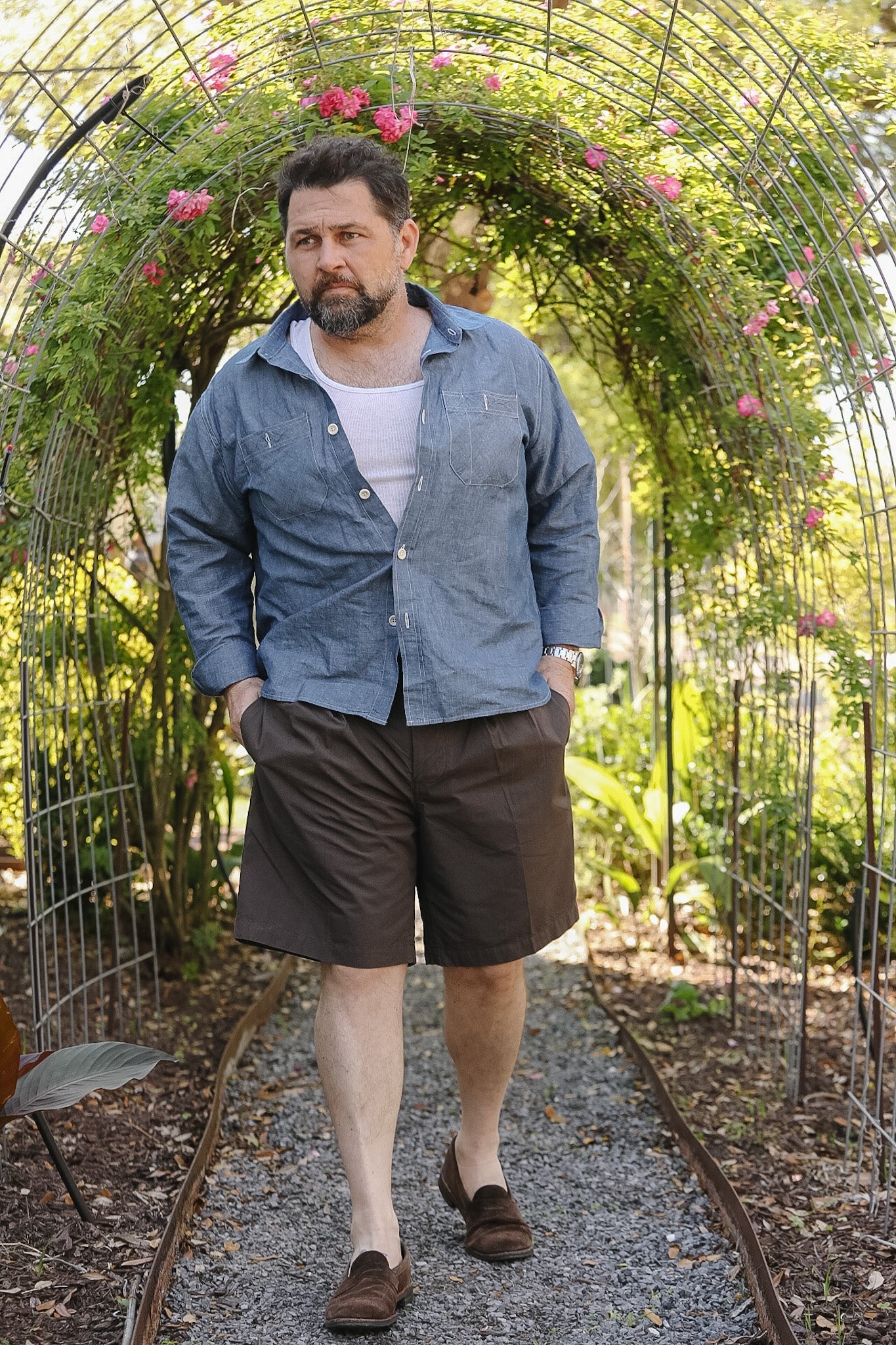 Man standing under a floral archway in a garden