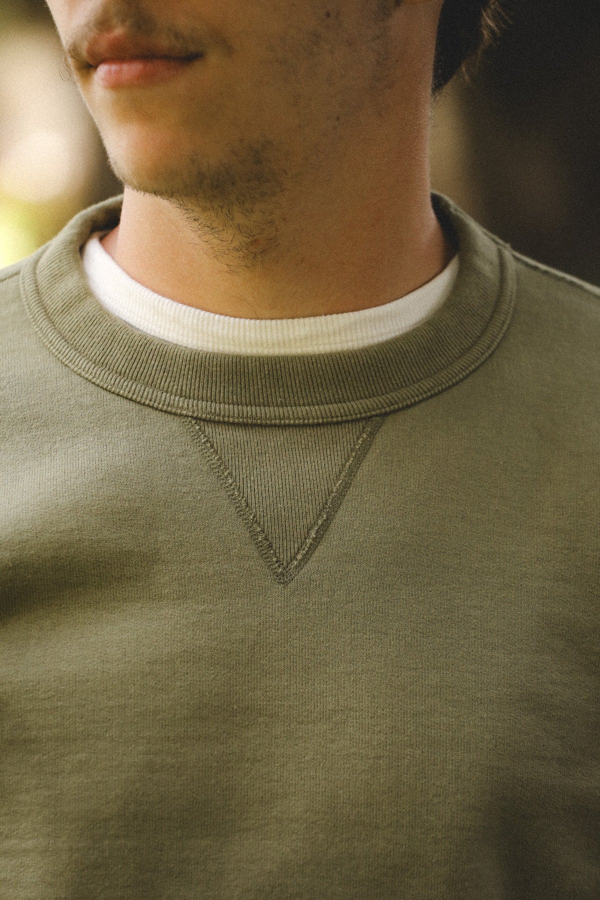 Close-up of a person wearing a green sweatshirt with a blurred background