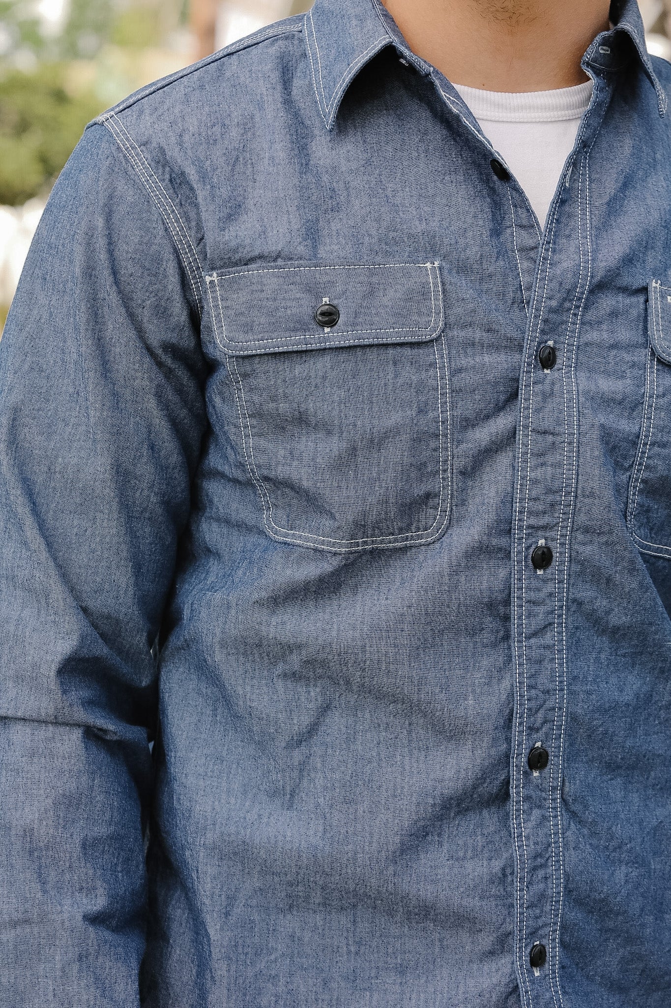 Blue denim shirt with a pocket and buttons on a blurred background