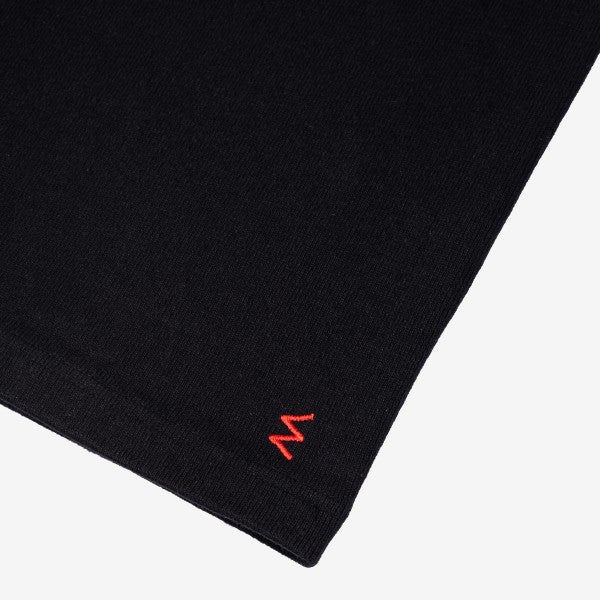 Close-up of black knit fabric with small red embroidered detail on Iron Shop Provisions apparel