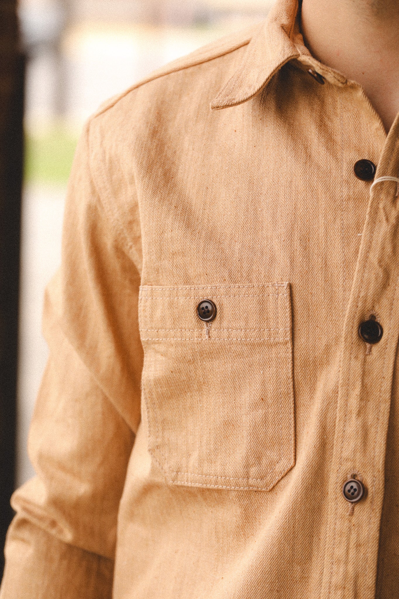 Close-up of a beige shirt with black buttons on a blurred background