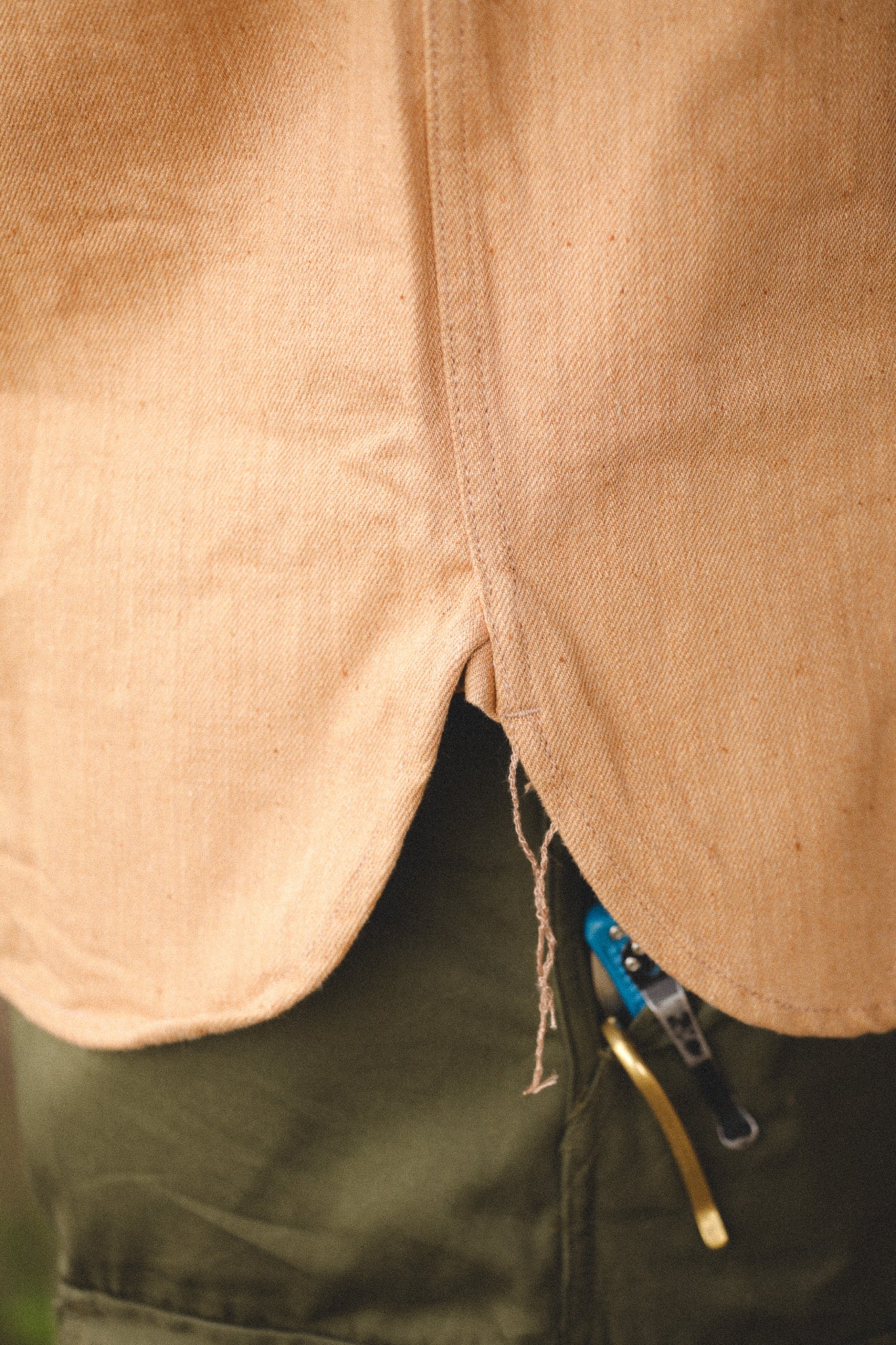 Close-up of a beige jacket with a blue zipper on a blurred background