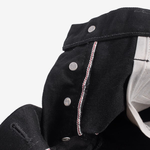 Close-up of black denim with visible silver rivets and red-white selvedge edge detail