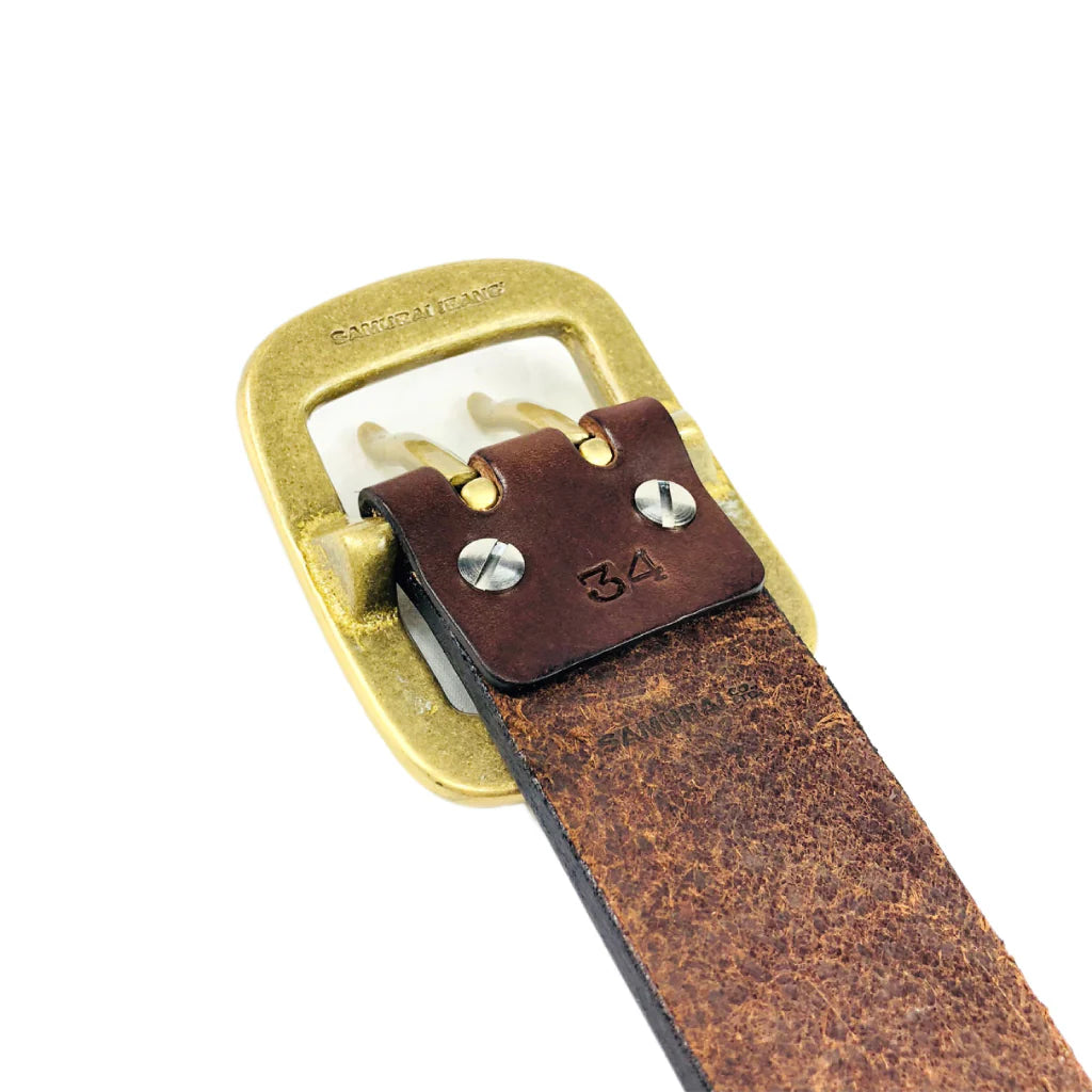 Close-up of brown leather belt with brass buckle stamped Samurai Jeans and size 34