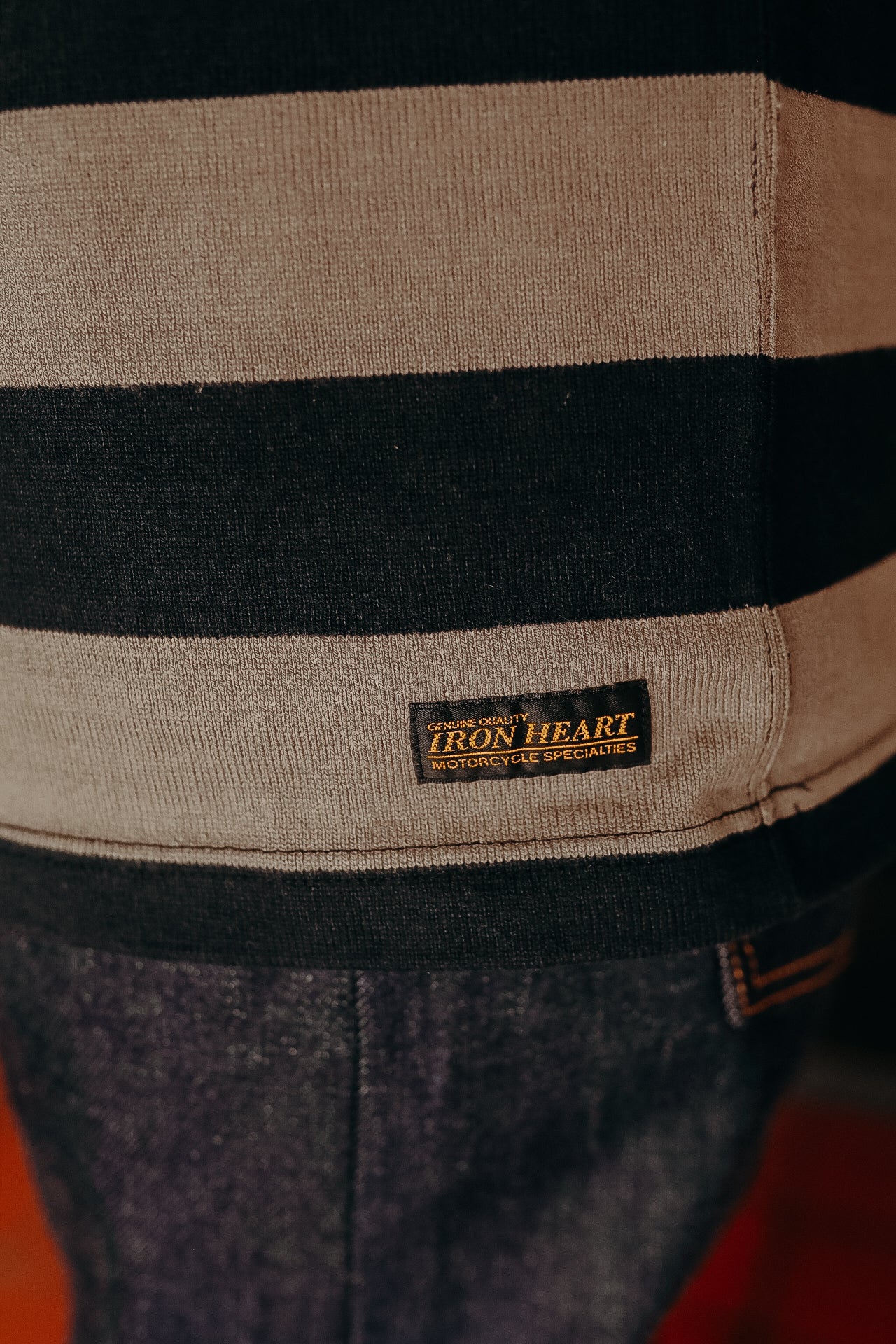Close-up of striped knit sweater with Iron Heart label and denim jeans detail