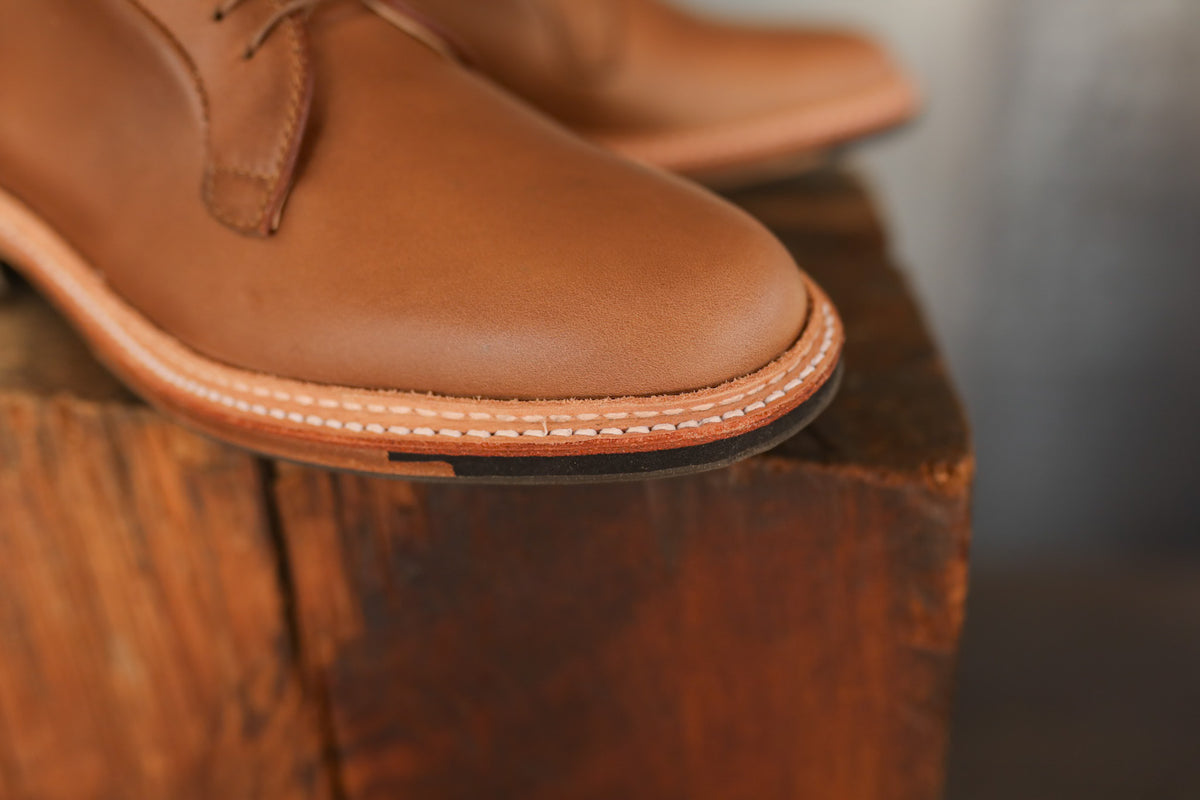 Brown leather shoes on a wooden surface with a blurred background