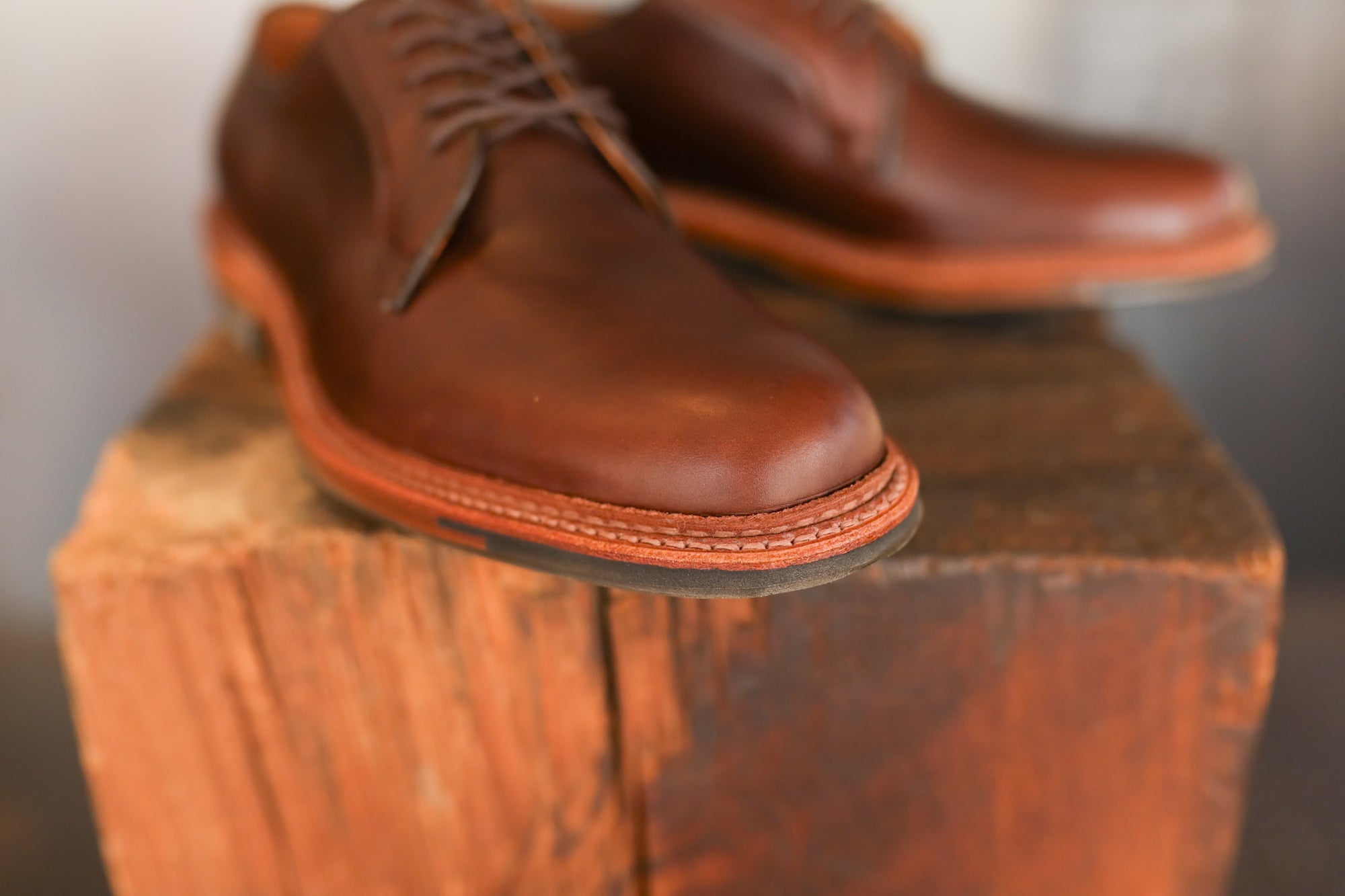 Pair of brown leather shoes on a wooden block with a blurred background