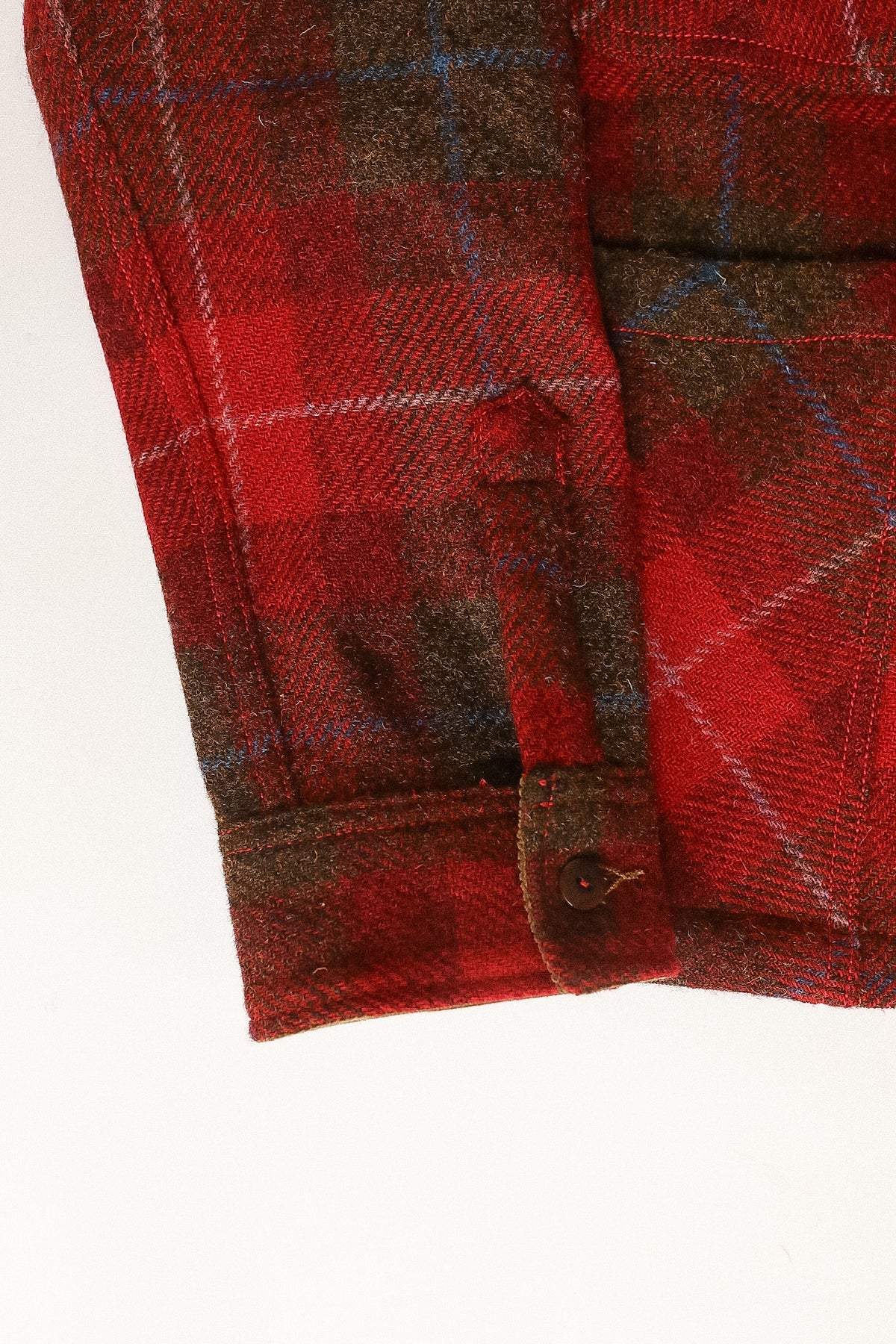 Close-up of a red plaid fabric with a button on a white background