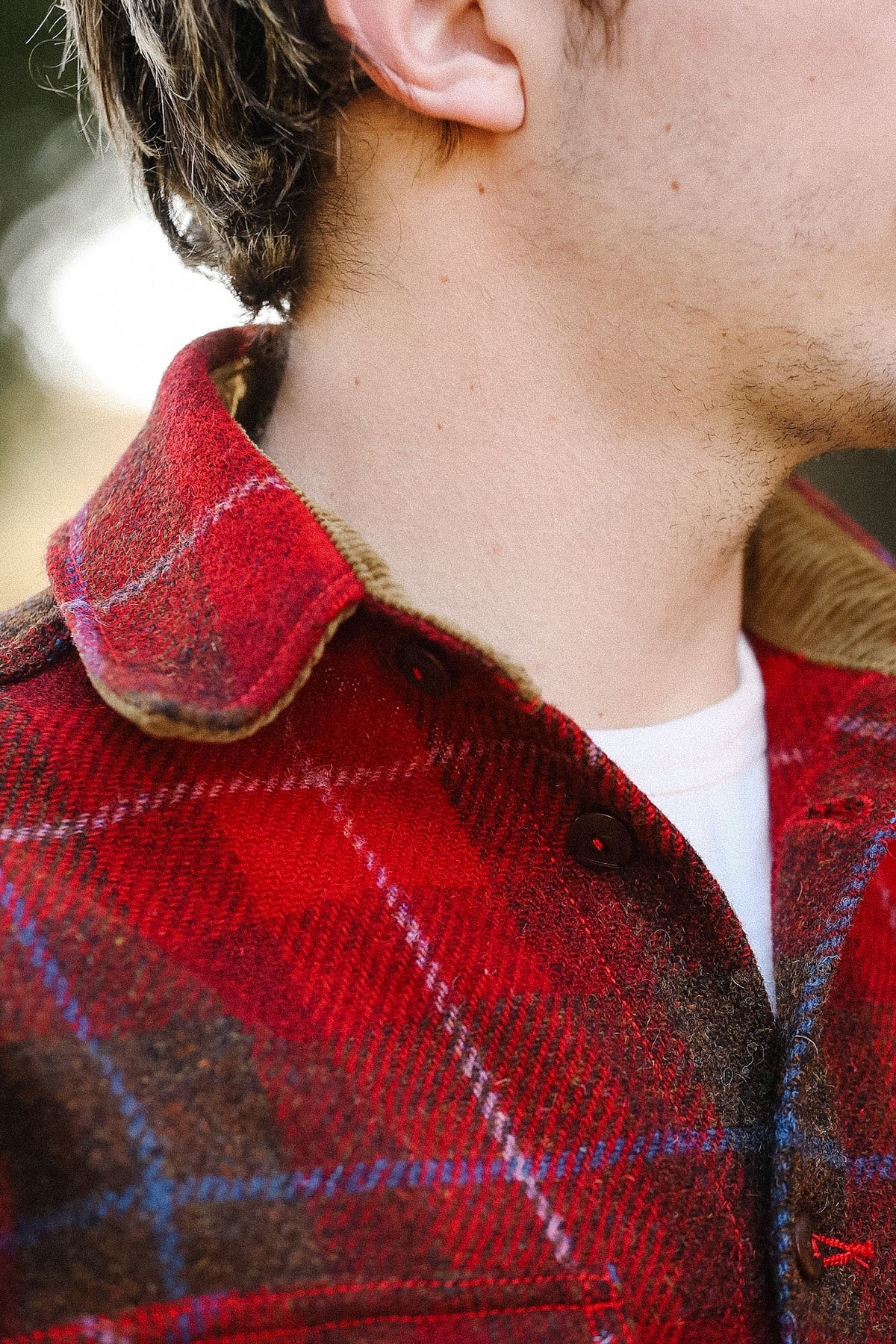 Close-up of a person wearing a red plaid shirt with a blurred background