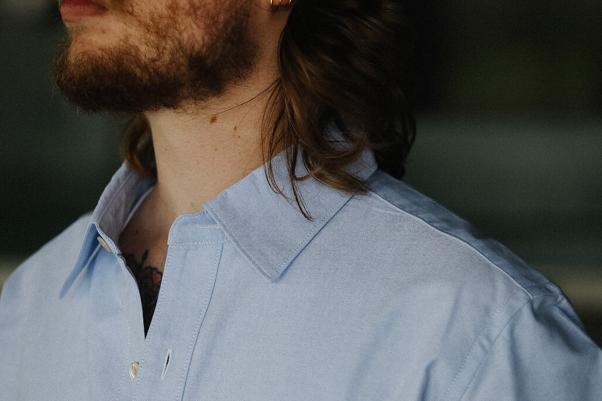 Close-up of a person wearing a light blue shirt with a blurred background
