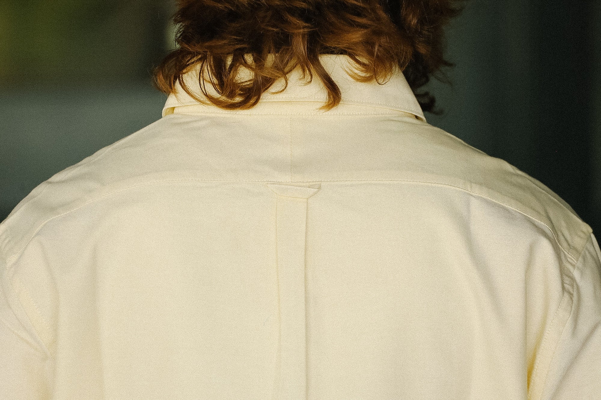 Back view of a person wearing a light-colored jacket with a blurred background