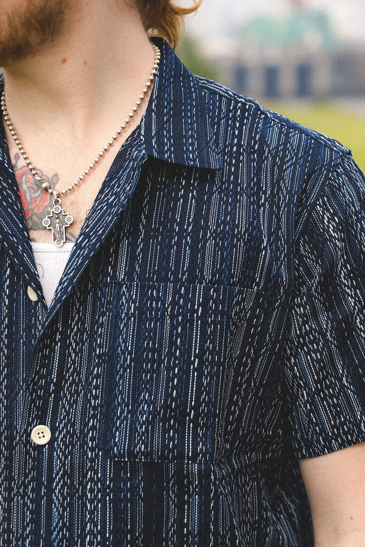Person wearing a dark blue patterned shirt with a blurred background