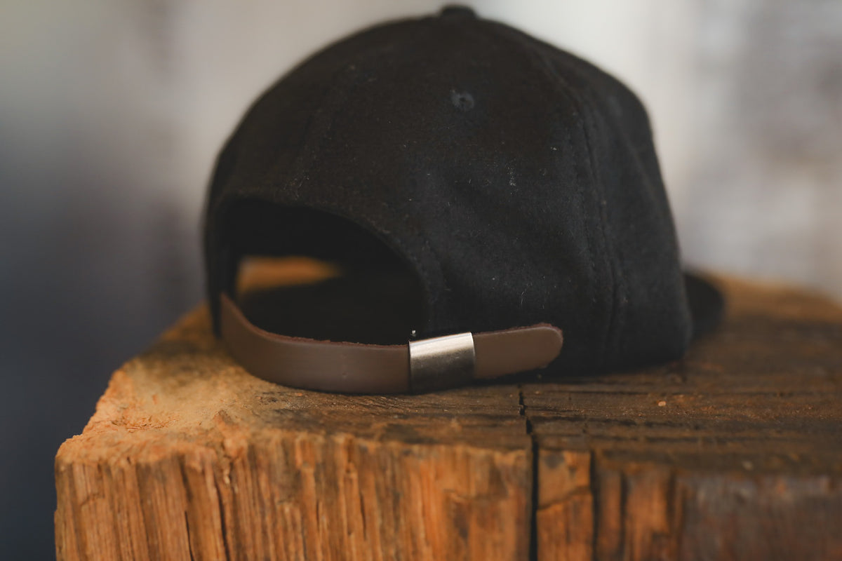Up close of a black baseball cap on wood block 