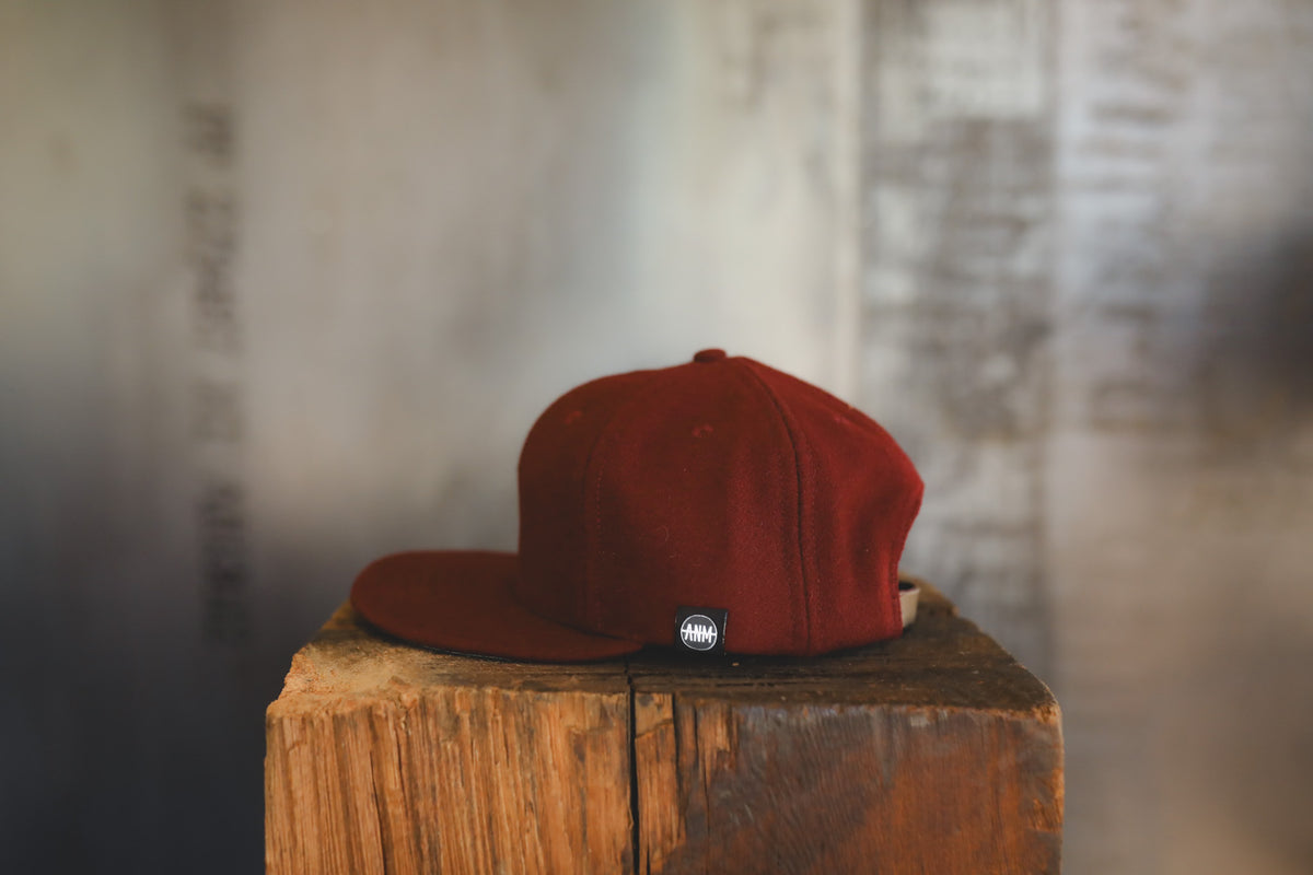 Dark maroon baseball cap on a wood block 