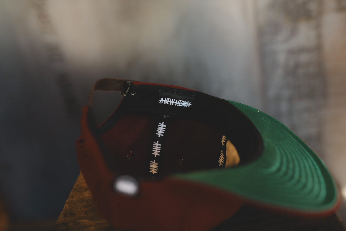 Dark maroon baseball cap on a wood block  with interior branding 