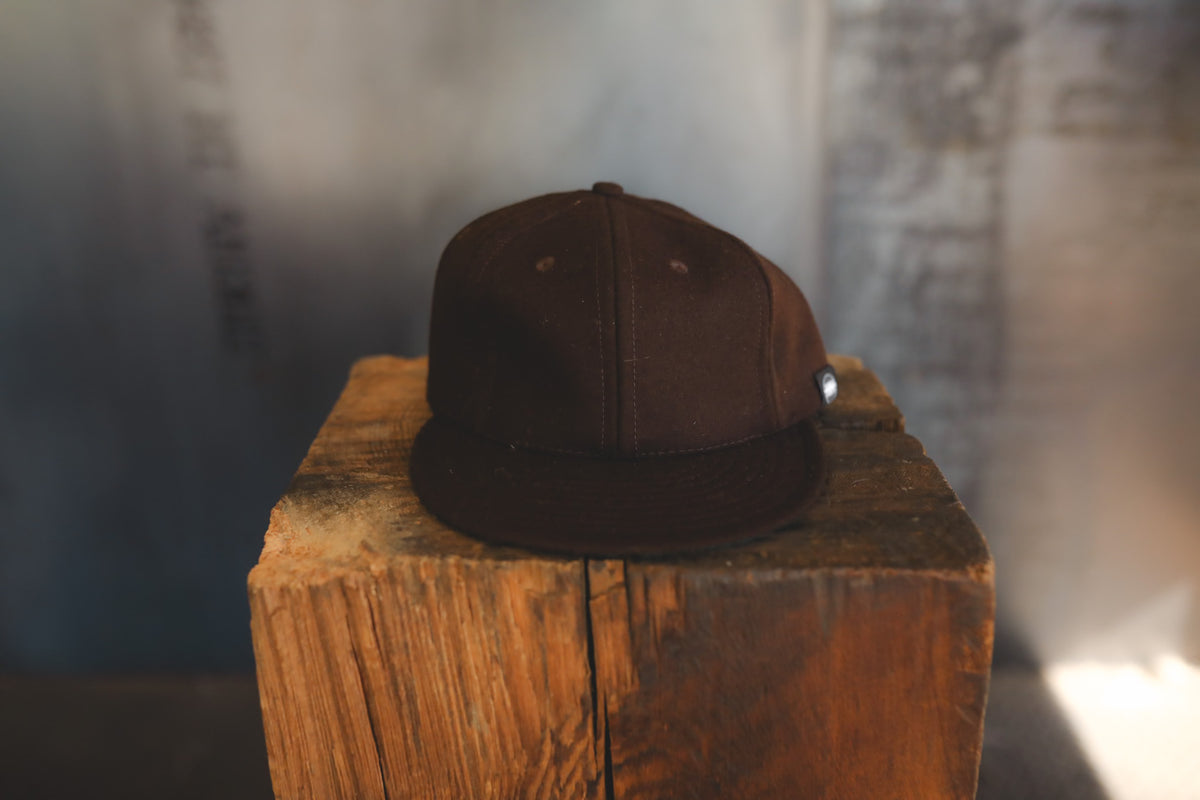 Up close of a brown baseball cap on wood block 