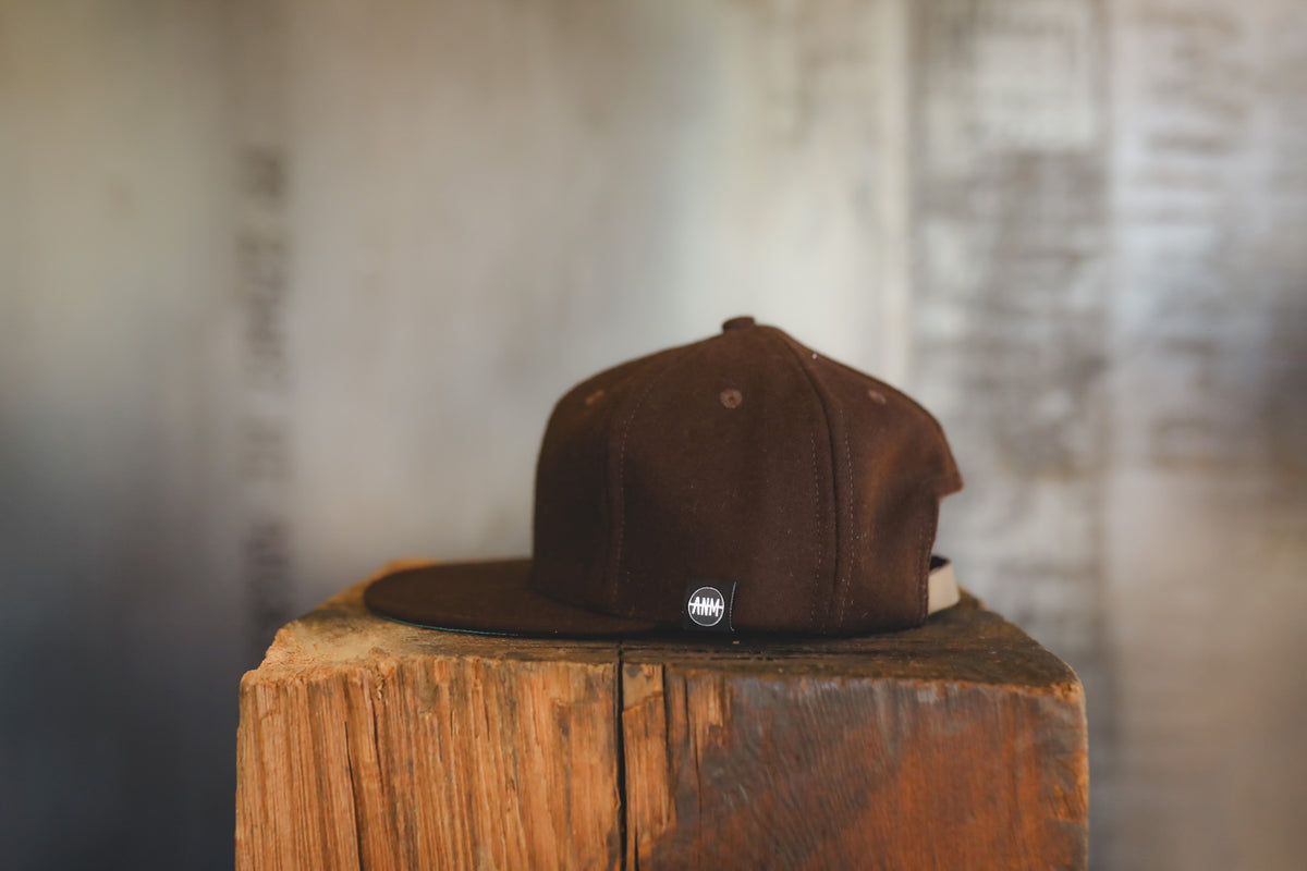 Up close of a brown baseball cap on wood block 