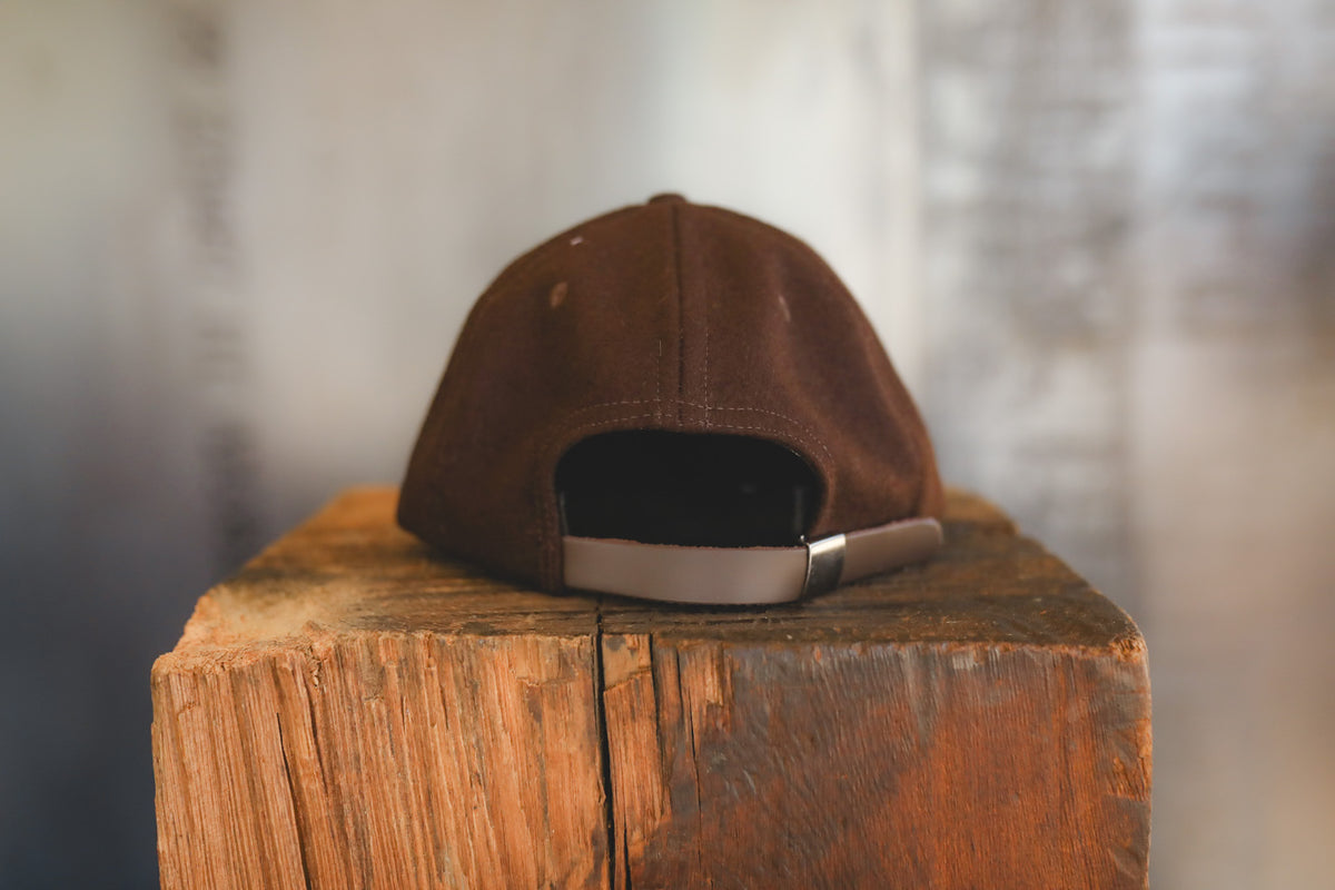 Up close of a brown baseball cap on wood block 